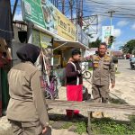 Petugas Satpol PP Kukar menertibkan seorang badut yang beraktivitas di kawasan lampu merah Simpang Unikarta, Tenggarong, Senin (22/6/2026).